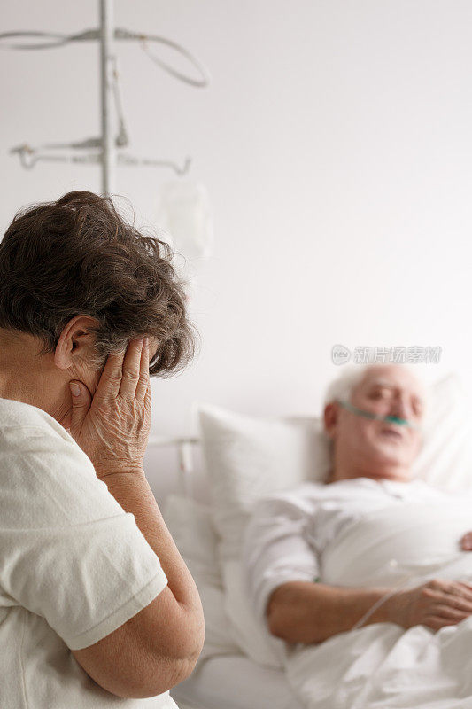 一个女人在她生病的丈夫旁边哭