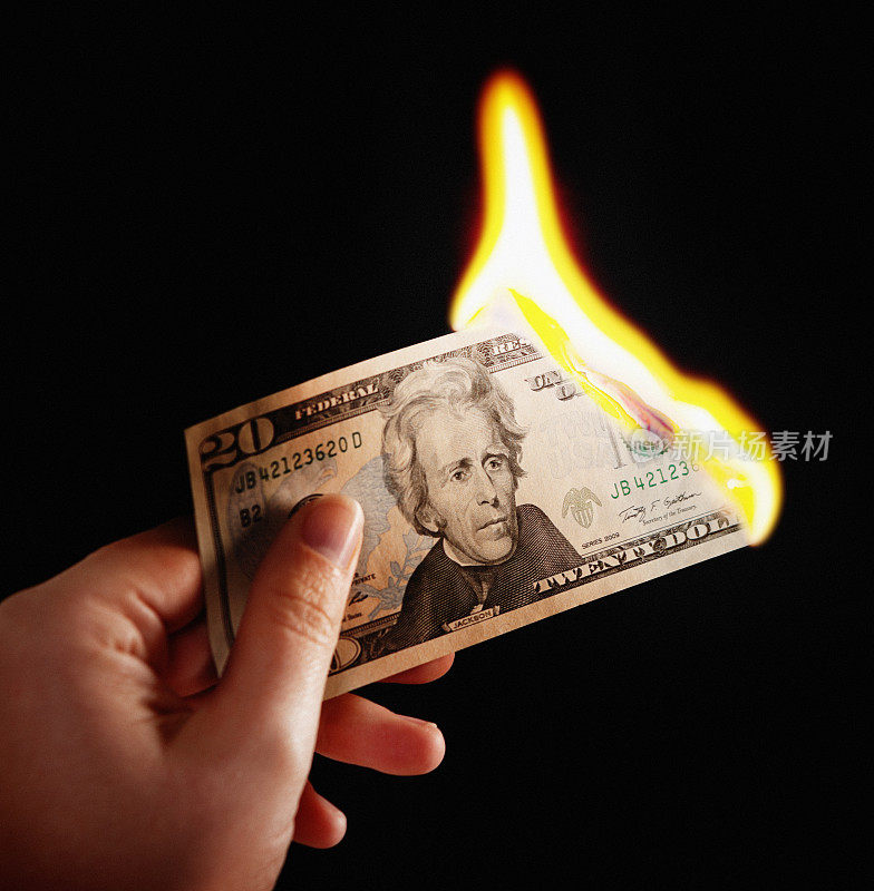 女性手里拿着燃烧的20美元钞票