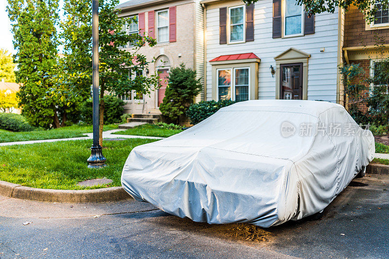 老式汽车覆盖的保护盖由联排别墅停车场潮湿的天气