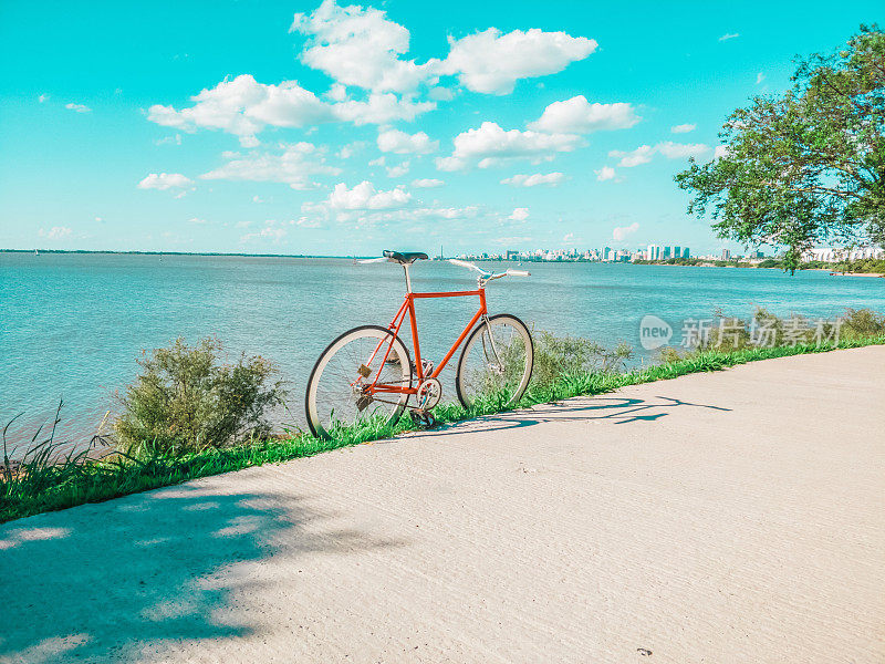 固定齿轮自行车没有刹车在凉爽的日落滨水边缘。怀旧复古的风格。城市在背景中，河流平静