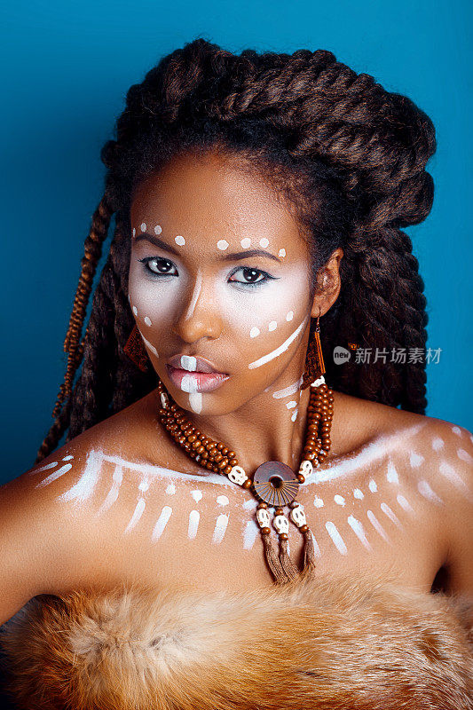 非洲风格的女人。迷人的年轻女子在民族珠宝。一个女人的近距离肖像与一个涂抹的脸。创意的妆容和明亮的风格。