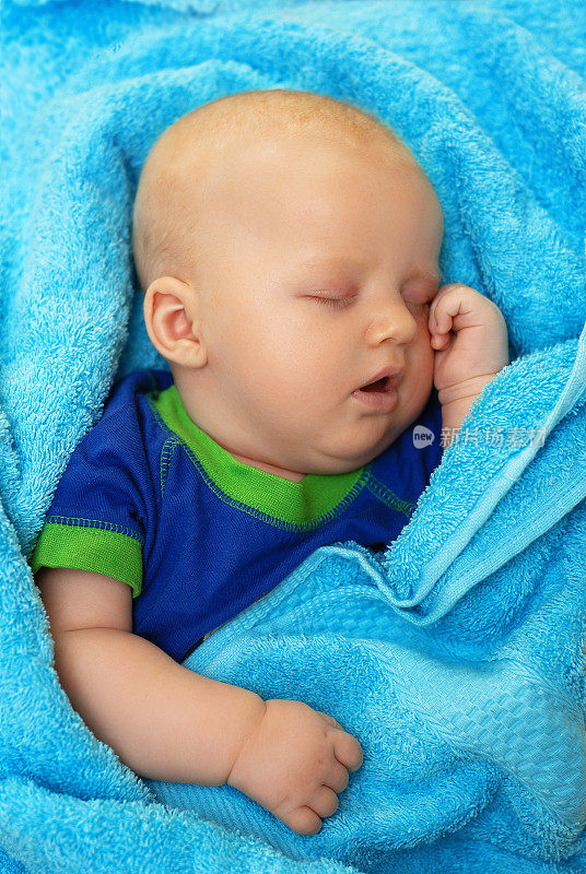 宝宝洗澡后裹着蓝色毛巾睡觉