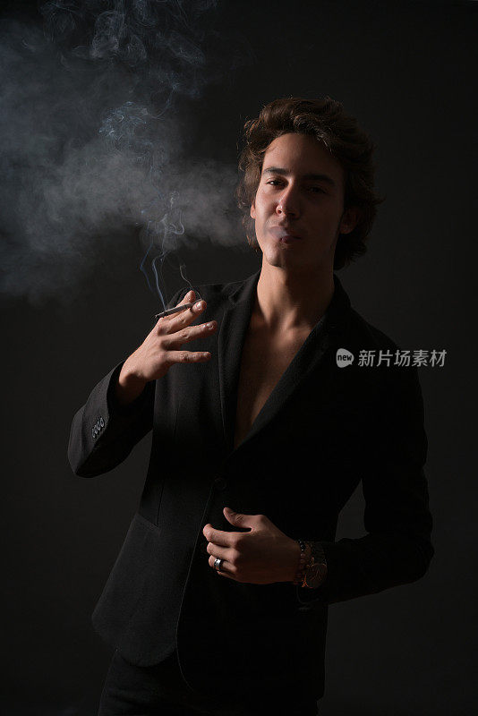 年轻男子的肖像在黑色背景上吸烟