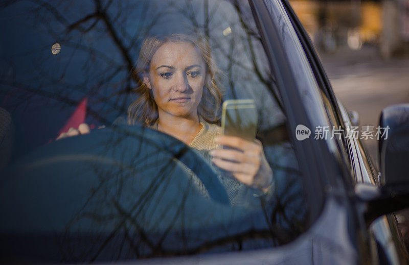 年轻女子一边开车一边用手机发短信。