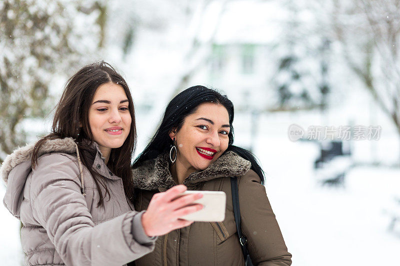 快乐的母女在雪中自拍