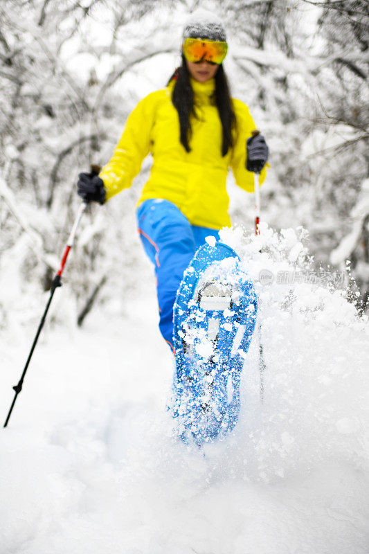 在冰冻的森林里，穿着雪鞋穿过厚厚的积雪的徒步旅行者