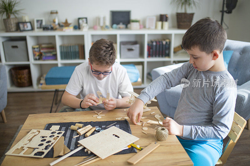 兄弟们正在为学校项目制作木制模型飞机