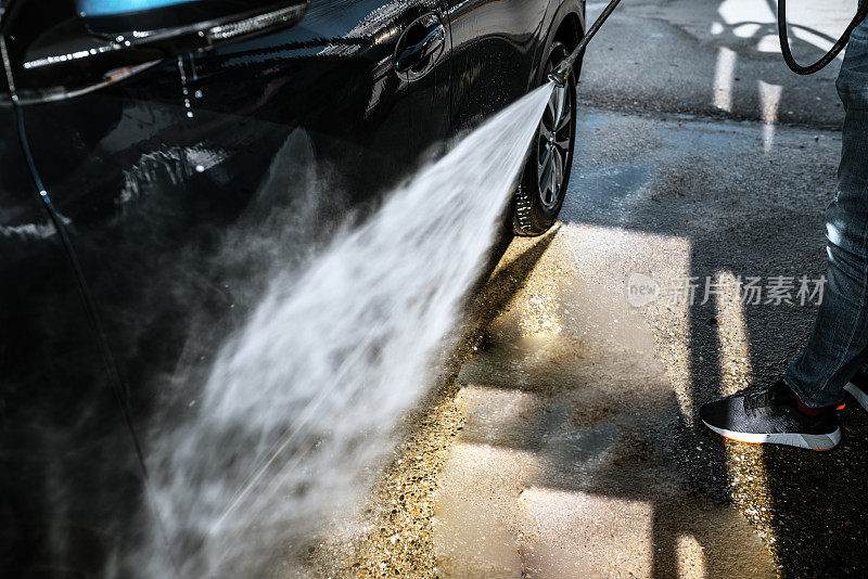 一名男子正在用高压清洗他的汽车