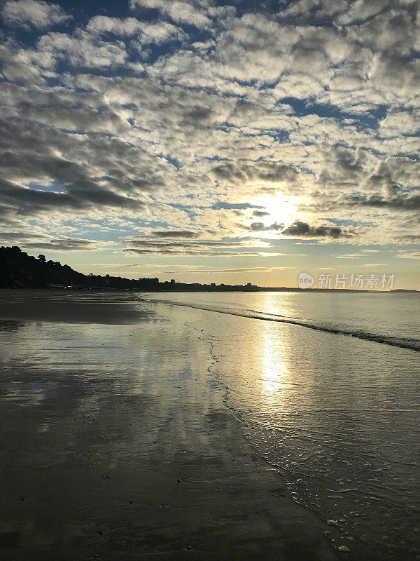 英国清晨海滩日出的图片，温和的海浪和潮汐拍打海岸，潮湿的沙子re云和粉红色的蓝天，伯恩茅斯海滩日出日落的照片，多塞特海岸线，英国西南部