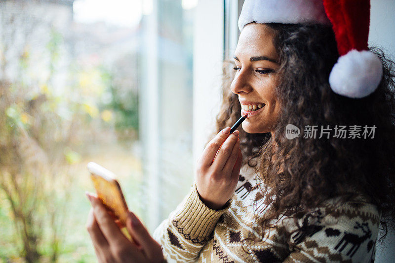 迷人的年轻女子在窗前化妆