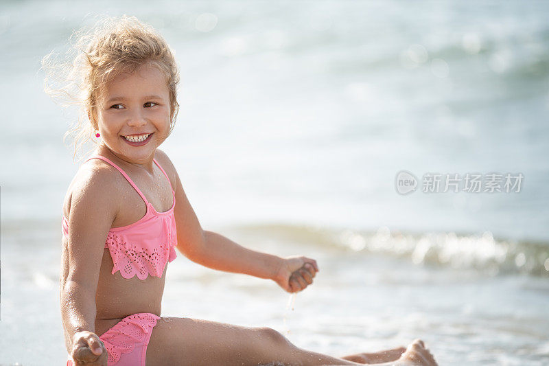 阳光明媚的海滩上，可爱的小女孩微笑着