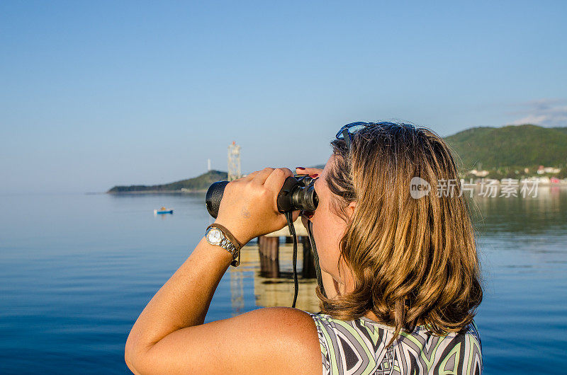 用双筒望远镜看海的女人
