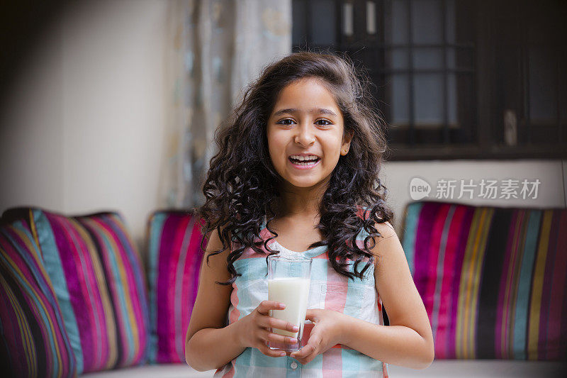 肖像一个开朗可爱的女孩微笑着拿着一杯牛奶的照片