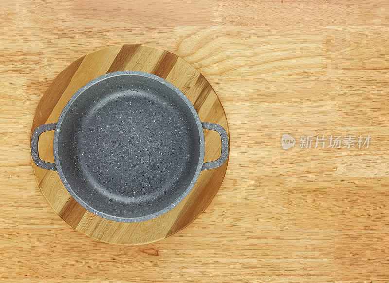 平底锅和圆砧板放在木桌上，俯视图
