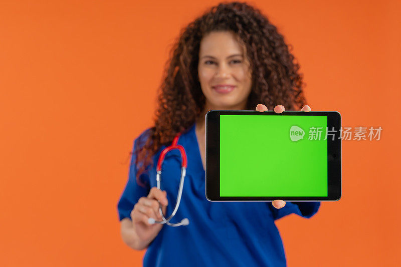 美丽的女医生显示数字平板与色度键绿色屏幕，积极的情绪