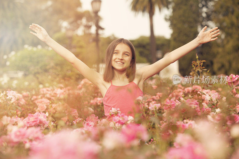 快乐的女孩在玫瑰花丛中嬉戏