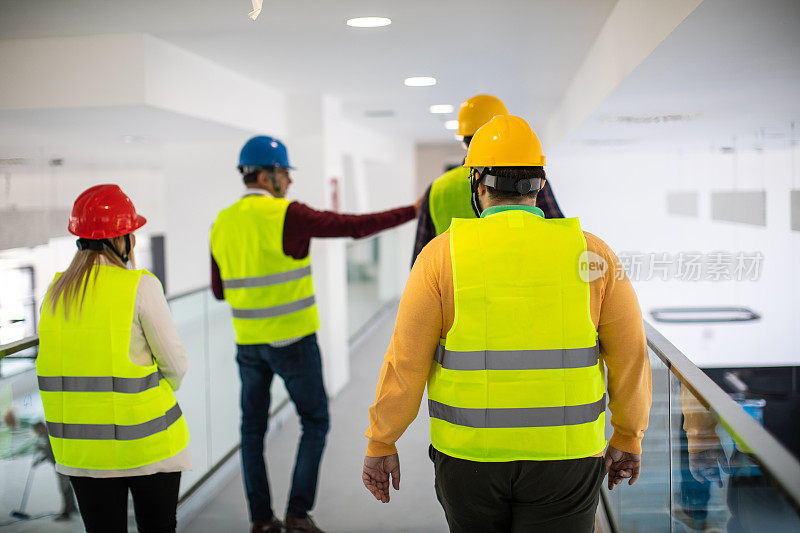 建筑师和建筑工人走过大楼，谈论工作进度