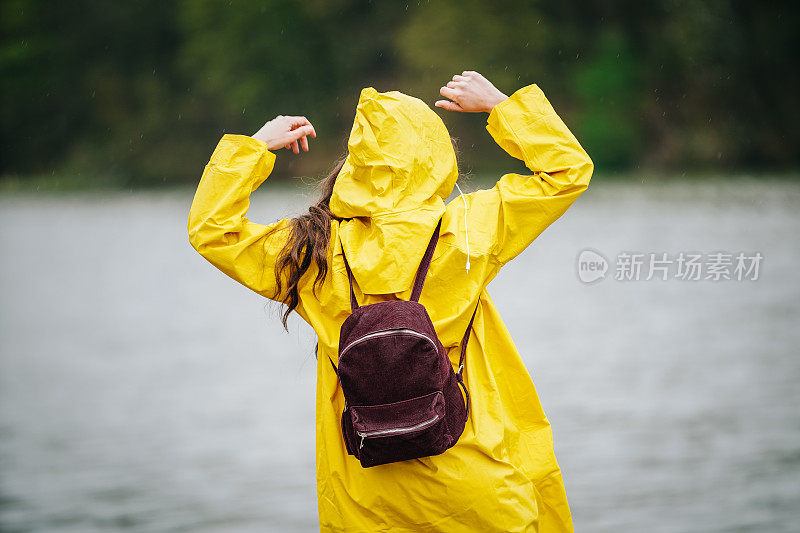 雨中穿着黄色雨衣的年轻女子