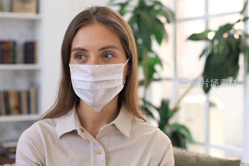 疫情期间，年轻女性在家中佩戴医用口罩。