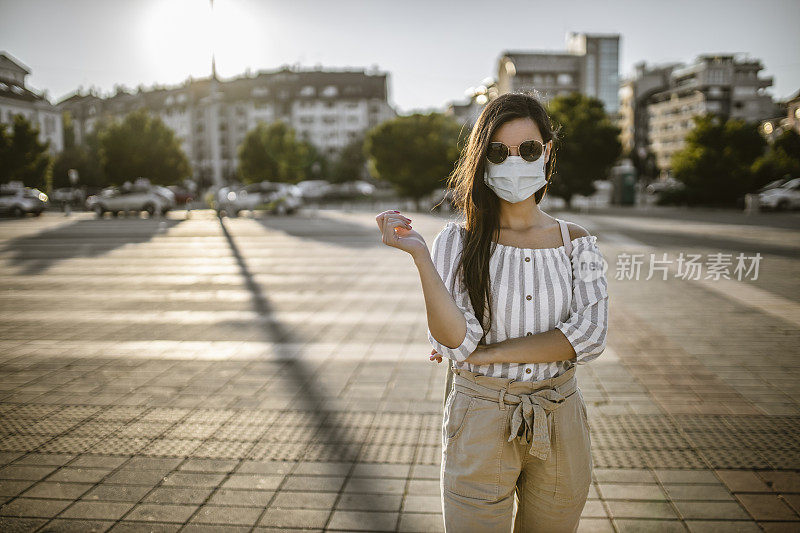封锁期间一个戴着外科口罩的女人在空荡荡的广场上