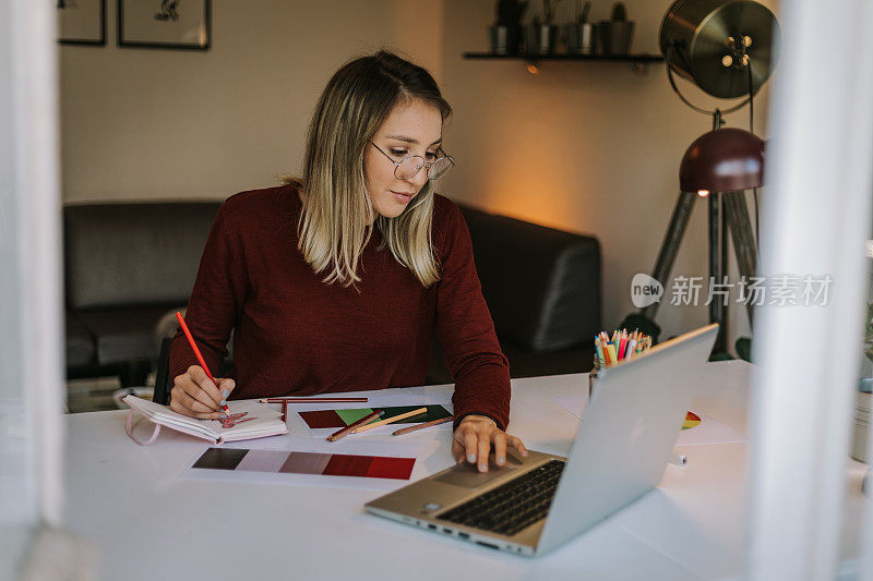 女性平面设计师是多任务，使用笔记本电脑和绘图草图