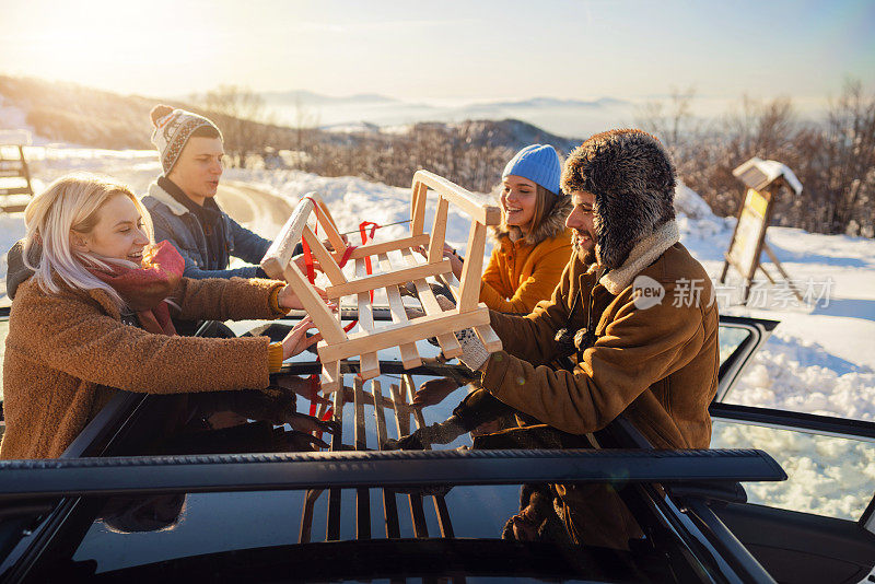 一群朋友在把雪橇绑在汽车行李架上