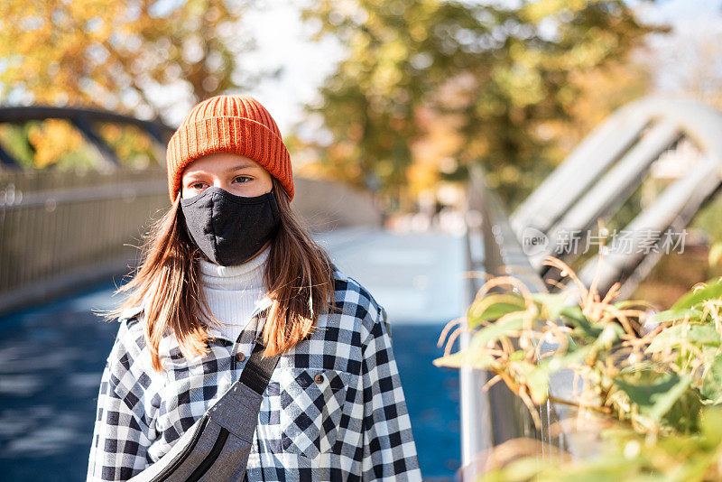 漂亮的女孩走在户外，戴着防护面罩