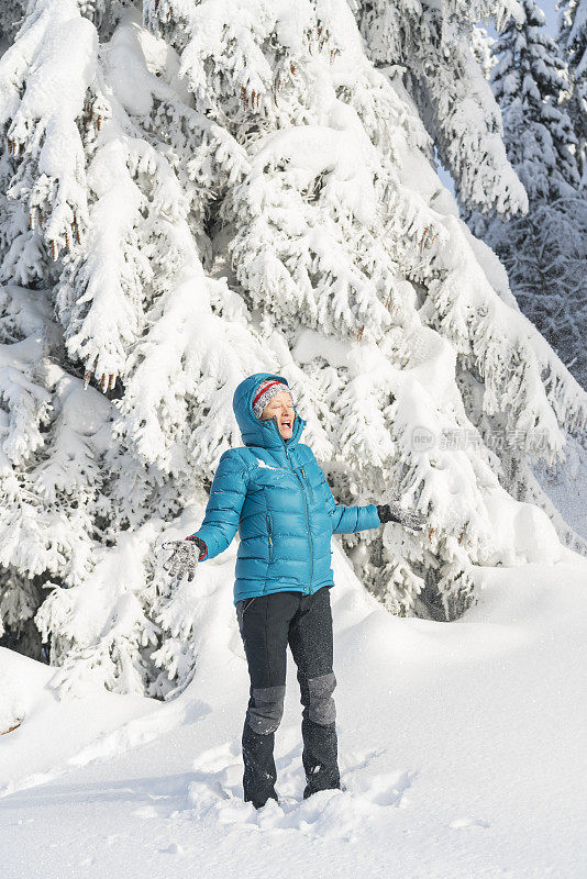 在冬天的森林里，成熟的女人穿着皮大衣向空中抛雪