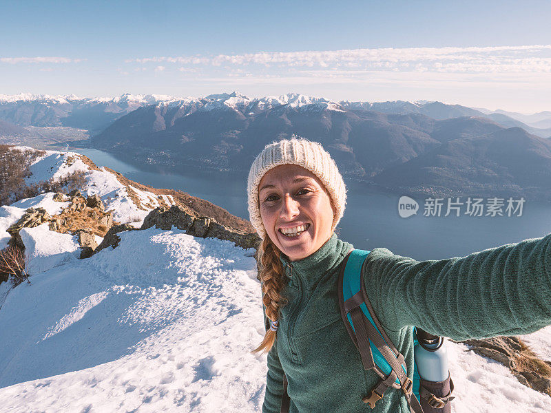 女徒步旅行者在山顶自拍。活跃的有吸引力的女人在徒步旅行与山脉和湖泊在远处的酷自拍