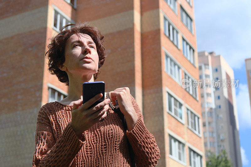 成熟的女人正在寻找城市里的地址。她正在用智能手机上的地图