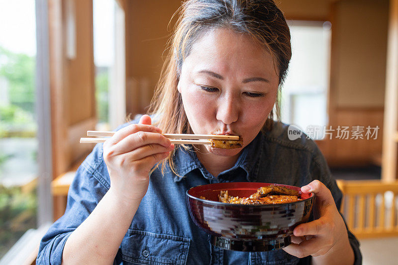 一个日本女人吃鳗鱼饭的特写