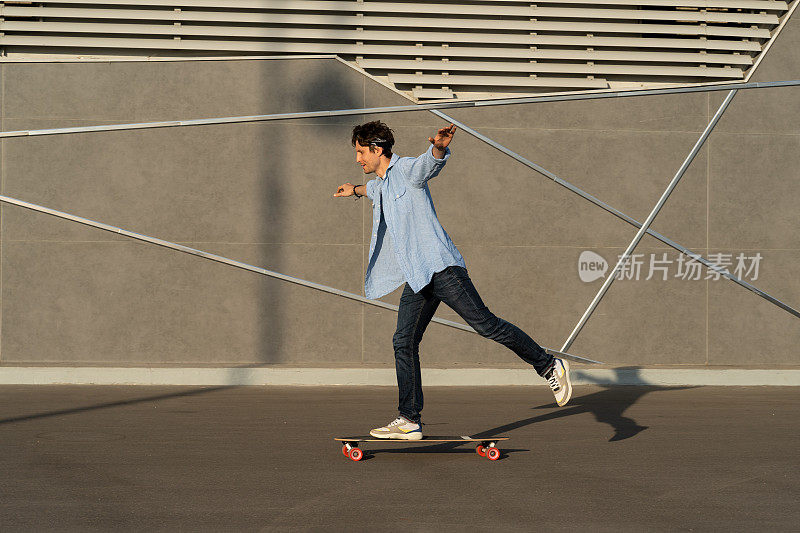 年轻人在城市街道滑板公园里骑长板。休闲潮男戴大手帕玩滑板