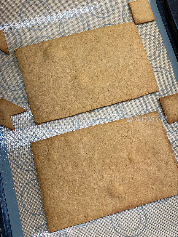 近距离的图像烤，自制的姜饼房子片在硅胶烤板，切割形状，姜饼面团形状与饼干切刀，家庭烘焙，升高的观点