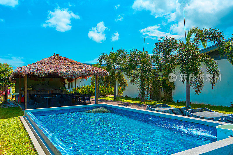 舒适的热带度假酒店，后院有游泳池。阳光明媚的晴天