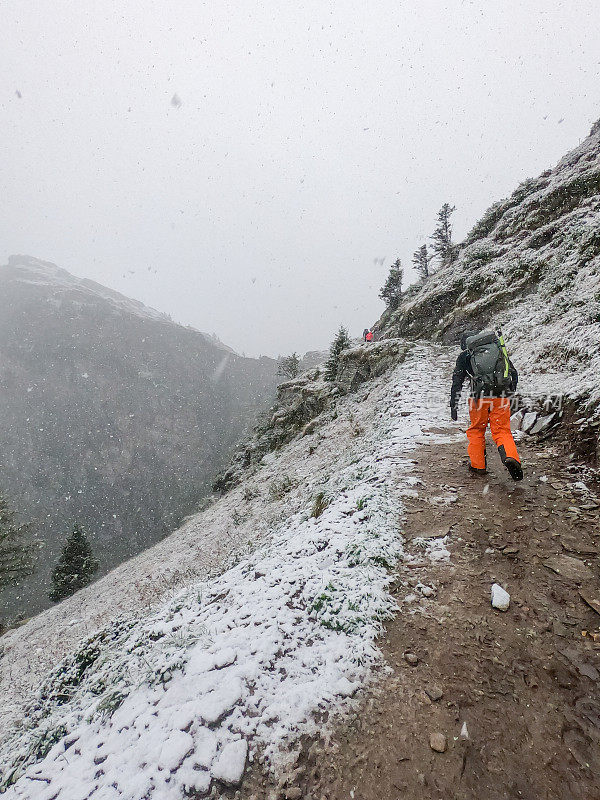 后视图的登山者在雪道上领导的方式到山顶