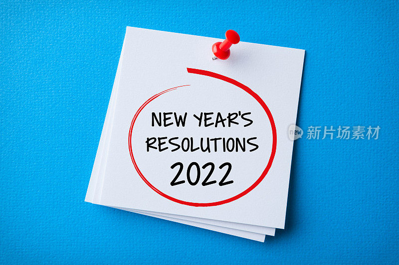 白色便利贴与新年2022决议和红色图钉在蓝色背景