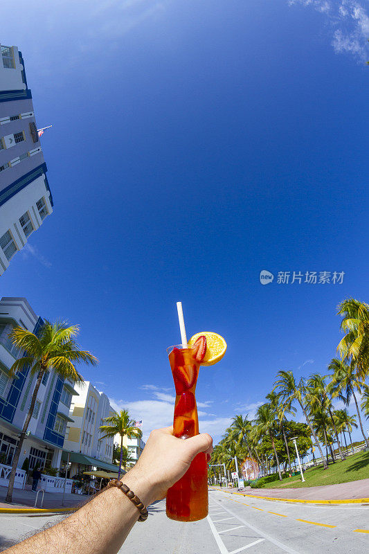 一名年轻的旅行男性一边享受他的假期，一边喝着鸡尾酒，在海洋大道，南海滩，迈阿密海滩，迈阿密，南佛罗里达，美国