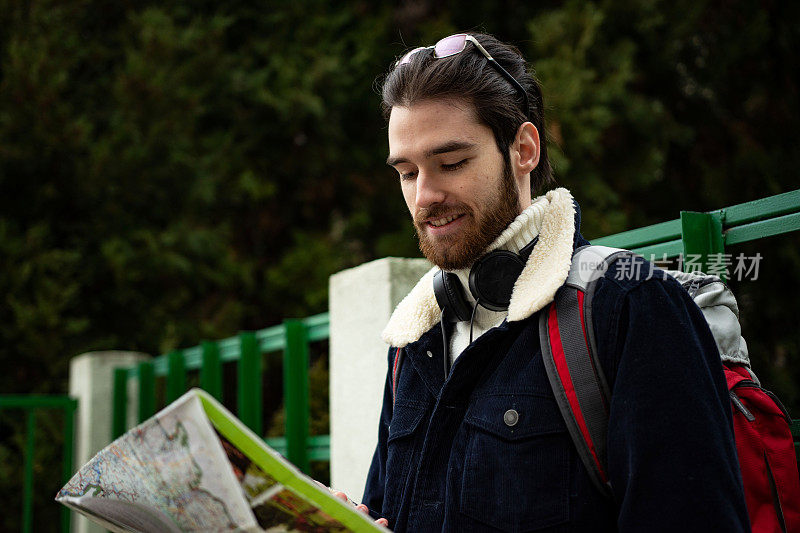 剪裁的镜头，一个英俊的年轻男子看着地图，而游览一个外国城市