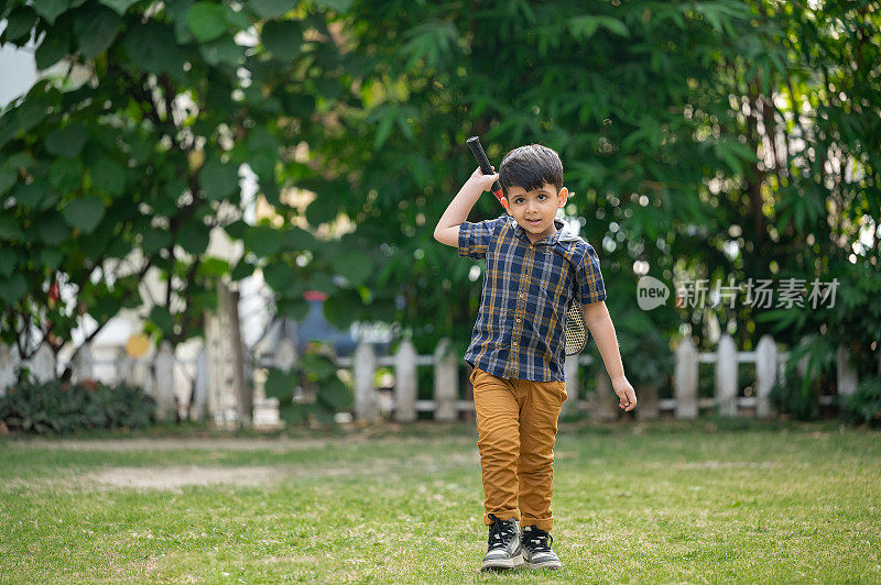亚洲印度小男孩在公园打羽毛球。