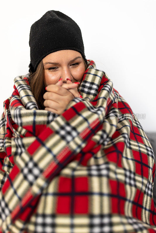 可怜的女人正裹着毯子取暖