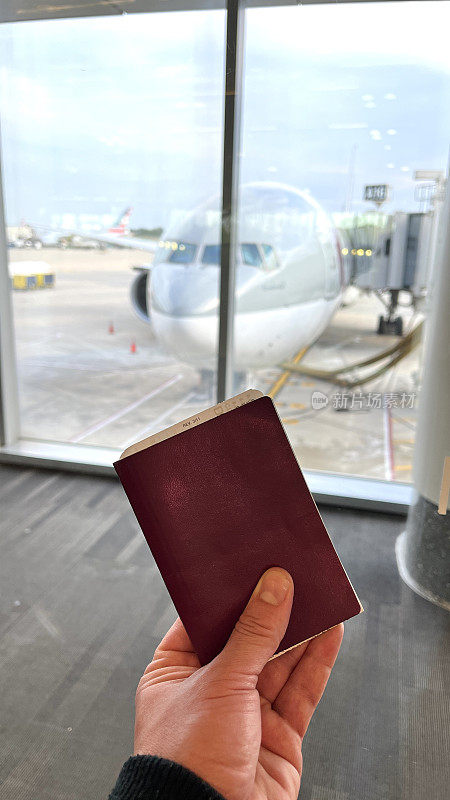 在费城国际机场，一个年轻的男子拿着他的护照和机票，在出发区等待乘坐他的飞机的视角拍摄。