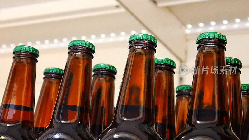 超市里许多棕色玻璃瓶的绿色瓶盖啤酒的特写