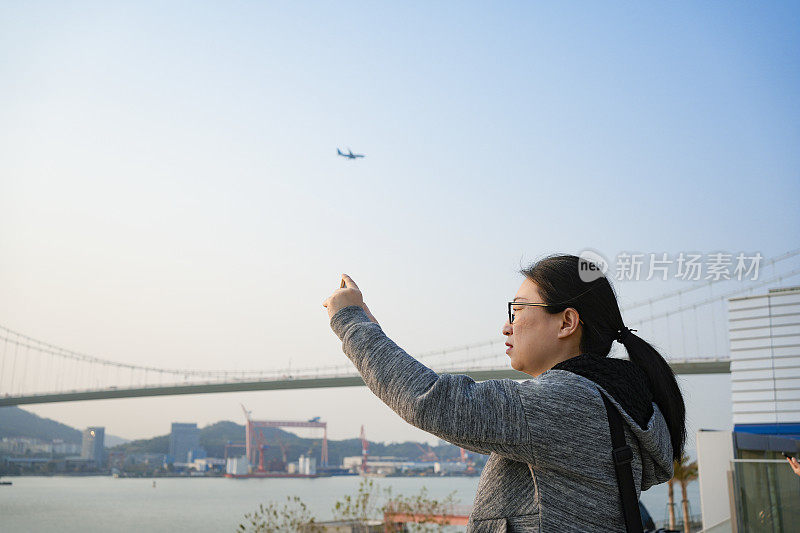 这位亚洲妇女正在用手机拍摄风景