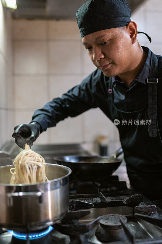 一个穿黑色制服的厨师正在准备饭菜。