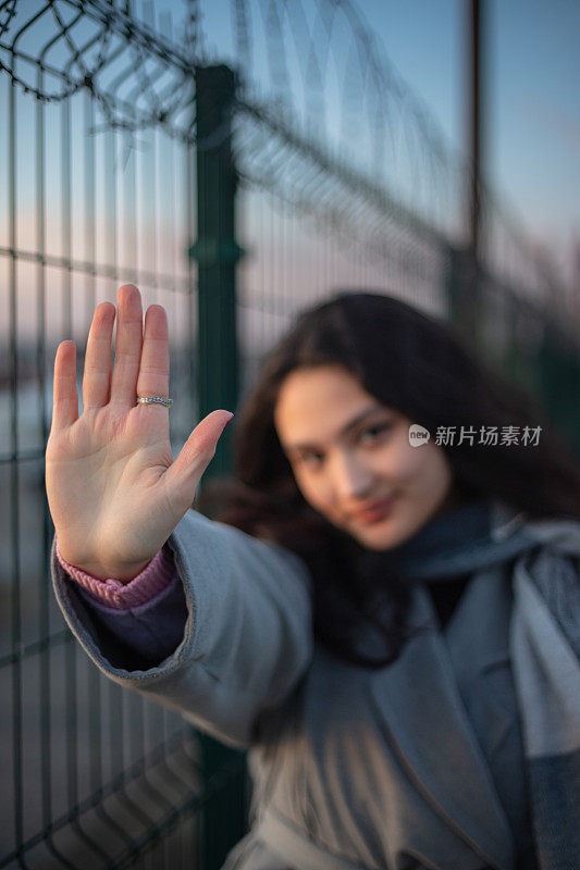 年轻的黑发女孩的肖像。
年轻女孩在看镜头时举手。