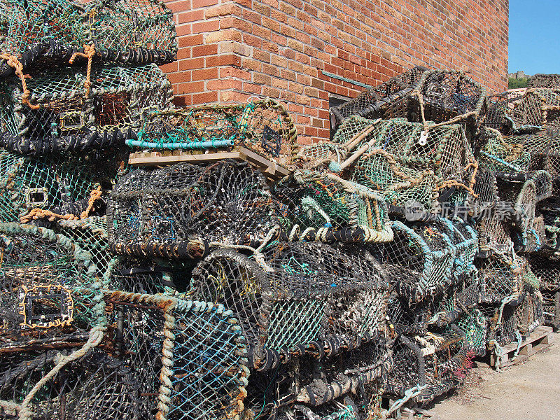 在斯卡伯勒港的一座建筑旁，堆放着传统捕捞甲壳类动物用的龙虾锅