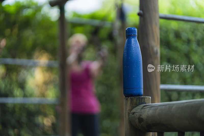 成年妇女锻炼时喝水从她的瓶子