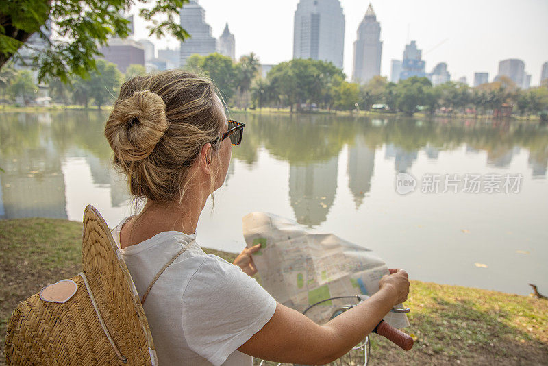 一名年轻女子骑着自行车探索亚洲，她看着地图