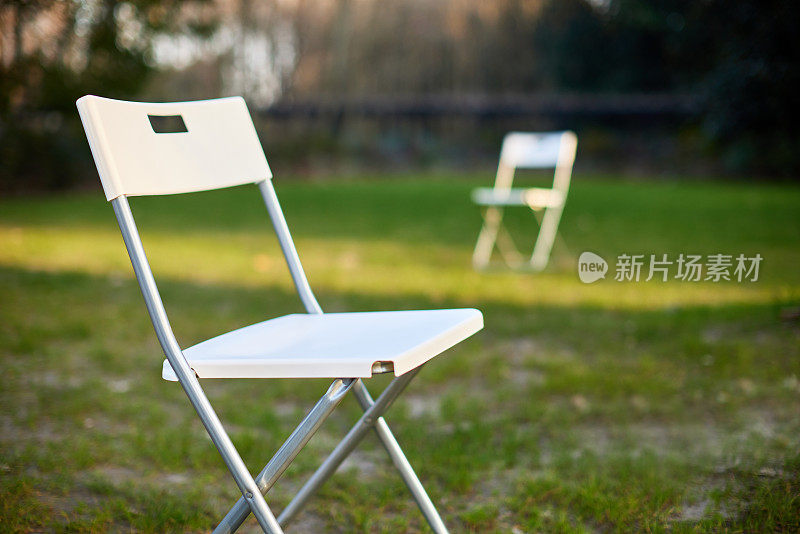 日落时草坪上的白色折叠椅