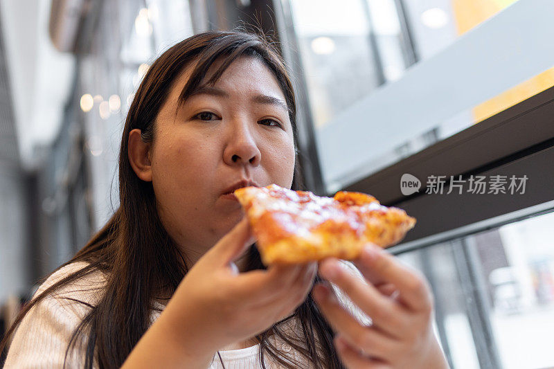 漂亮的年轻女子在咖啡馆吃披萨。